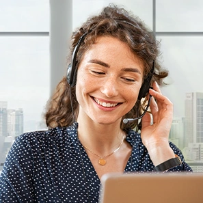 Mitarbeiterin im Kunden-Service blickt lächelnd auf Bildschirm