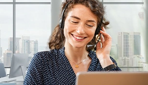 Mitarbeiterin im Kundenservice blickt lächelnd auf ihren Bildschirm