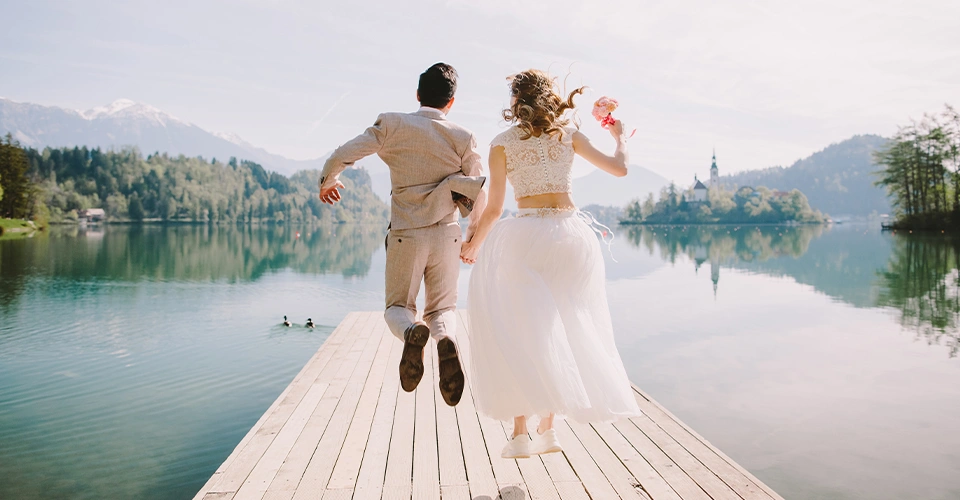 Wedding couple on a jetty in front of lake and mountains